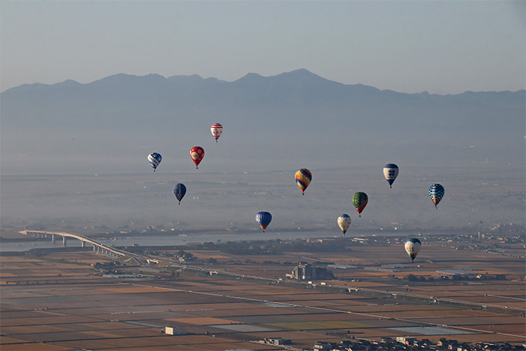 佐賀平野の上空を飛ぶ10機の熱気球の写真
