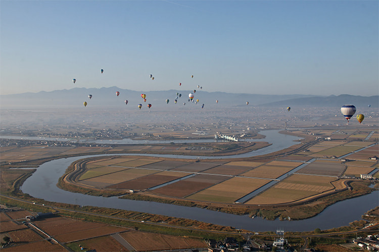 佐賀平野の牛津川上空を飛ぶ熱気球群の写真