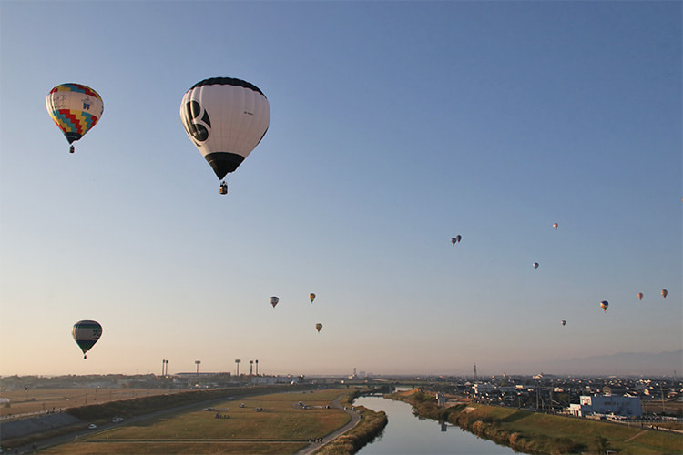 嘉瀬川上を飛ぶ白黒の熱気球の写真